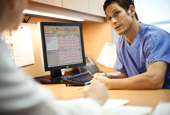 Médecin discutant avec un patient en regardant ECG Dématérialisé